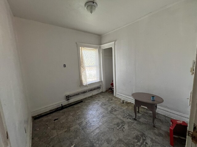 tiled empty room with a baseboard heating unit