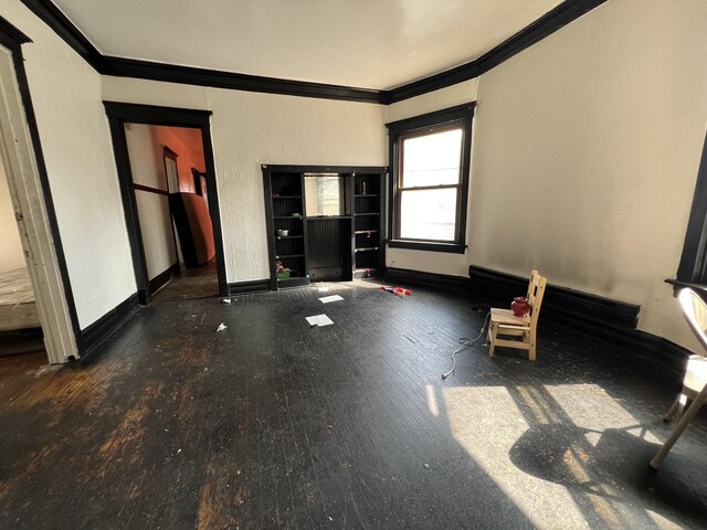 unfurnished living room with crown molding and wood-type flooring