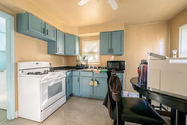 kitchen featuring gas range gas stove, sink, ceiling fan, and light tile patterned floors