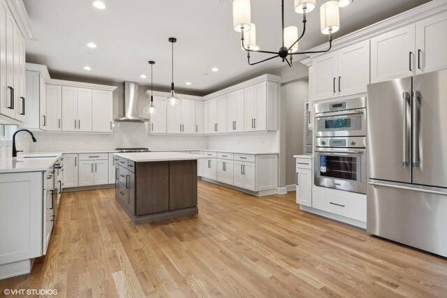 kitchen with tasteful backsplash, stainless steel appliances, light hardwood / wood-style floors, wall chimney exhaust hood, and sink