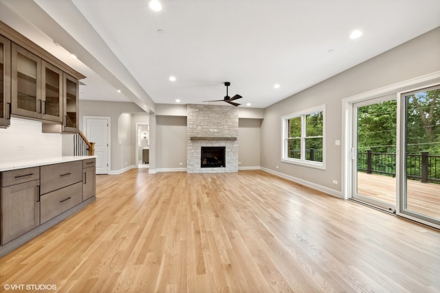 unfurnished living room with a fireplace, light hardwood / wood-style floors, and ceiling fan