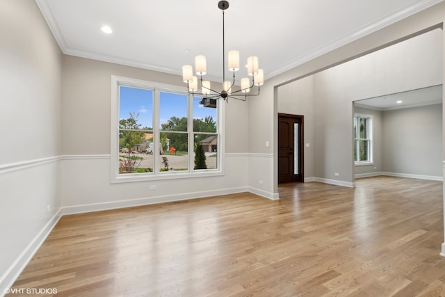 spare room with ornamental molding, light hardwood / wood-style flooring, and an inviting chandelier