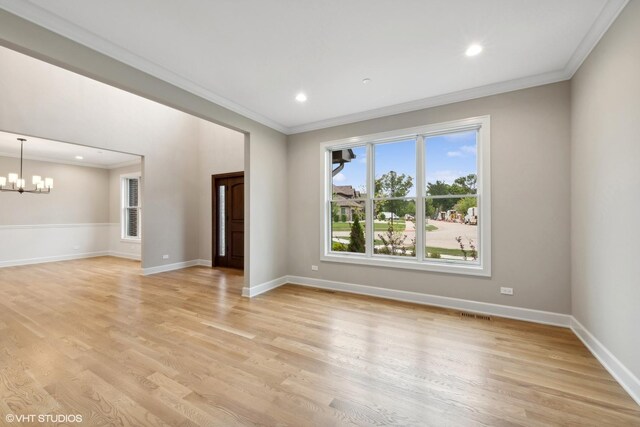 unfurnished living room with plenty of natural light, a chandelier, light hardwood / wood-style flooring, and ornamental molding