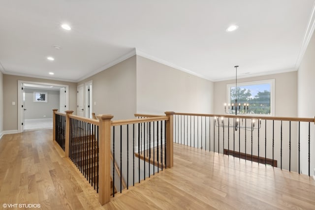 hallway with light hardwood / wood-style floors, a notable chandelier, and ornamental molding