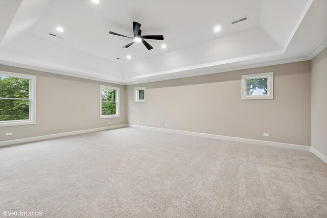 spare room featuring ceiling fan, a tray ceiling, and light colored carpet