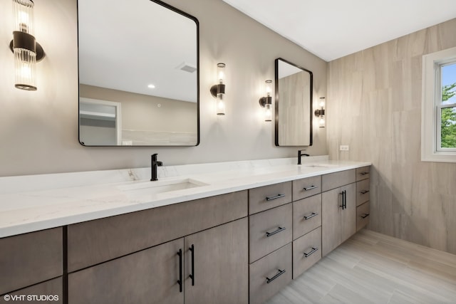 bathroom with tile patterned floors, tile walls, and dual bowl vanity