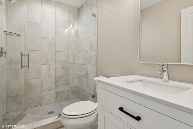 bathroom with tiled shower, toilet, and vanity