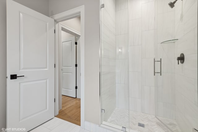 bathroom with a shower with door and hardwood / wood-style floors