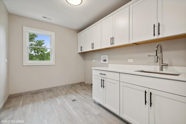 laundry area with light hardwood / wood-style floors, sink, cabinets, and hookup for a washing machine