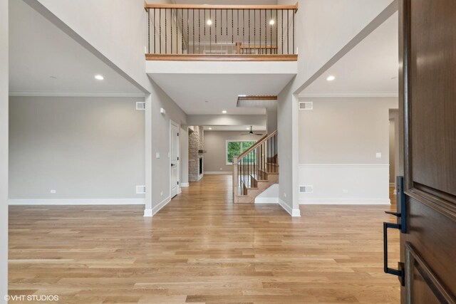 foyer featuring ceiling fan, a high ceiling, light hardwood / wood-style flooring, and ornamental molding