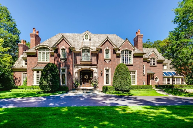 view of front of house with a balcony and a front lawn