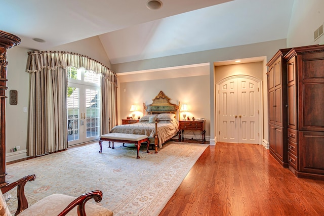 bedroom featuring vaulted ceiling, access to outside, light wood-type flooring, and french doors