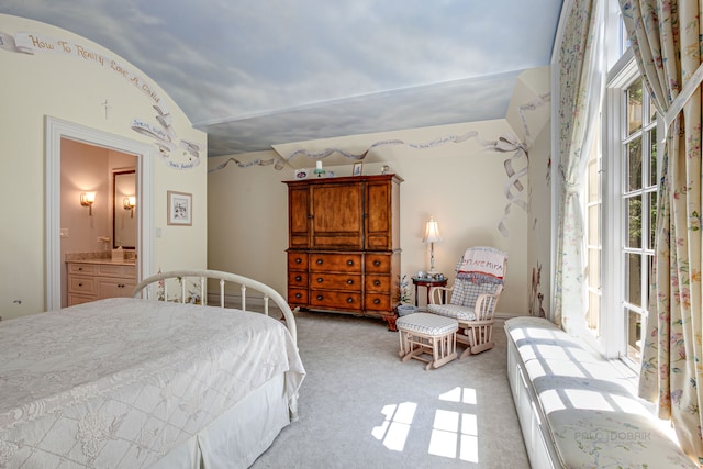 bedroom featuring lofted ceiling, light carpet, multiple windows, and ensuite bath