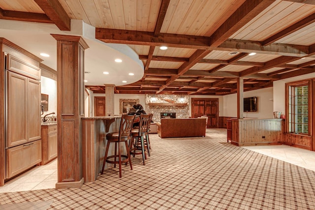 kitchen featuring a large fireplace, beamed ceiling, coffered ceiling, ornate columns, and light tile patterned floors