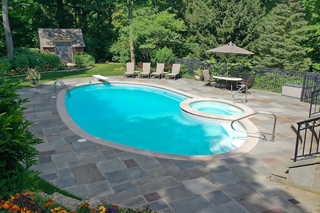 view of swimming pool with an in ground hot tub, a patio, a diving board, and an outbuilding