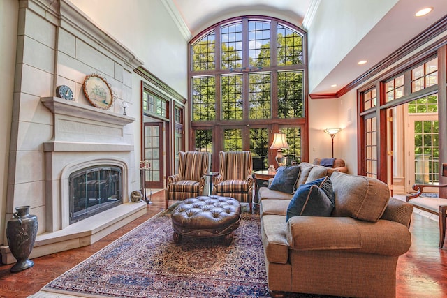 living room with crown molding, wood-type flooring, and a towering ceiling