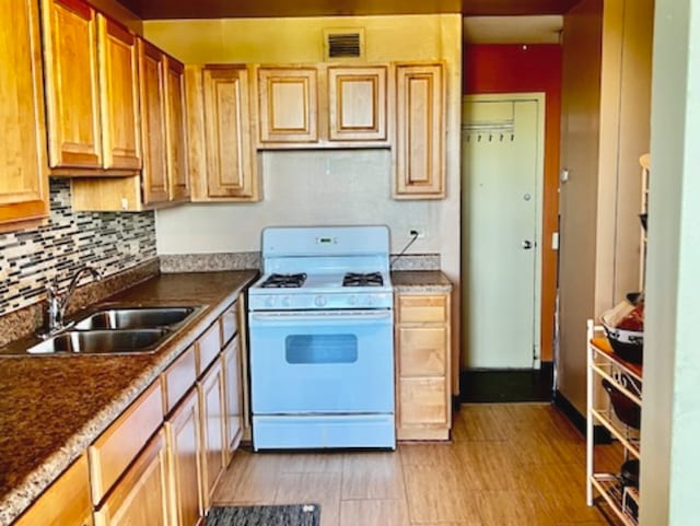 kitchen featuring backsplash, sink, and white range with gas cooktop