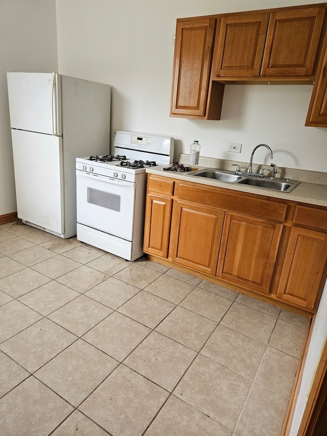 kitchen featuring light tile patterned floors, white appliances, and sink