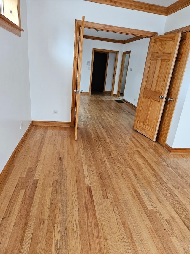 empty room with ornamental molding and light hardwood / wood-style flooring