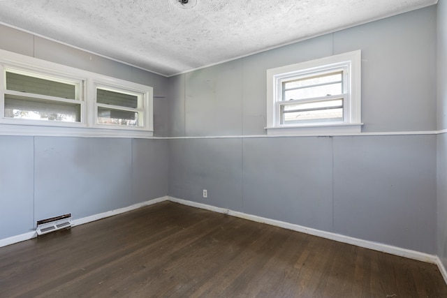 spare room with dark wood-type flooring and a textured ceiling