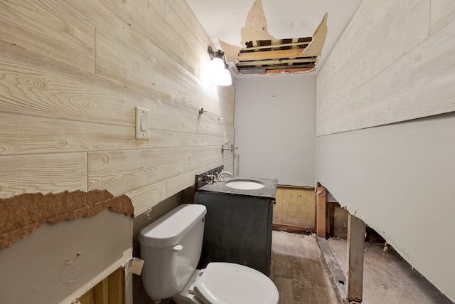 bathroom featuring vanity, toilet, and wooden walls