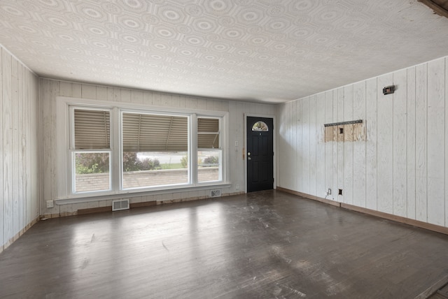 foyer entrance featuring dark wood-type flooring and wood walls