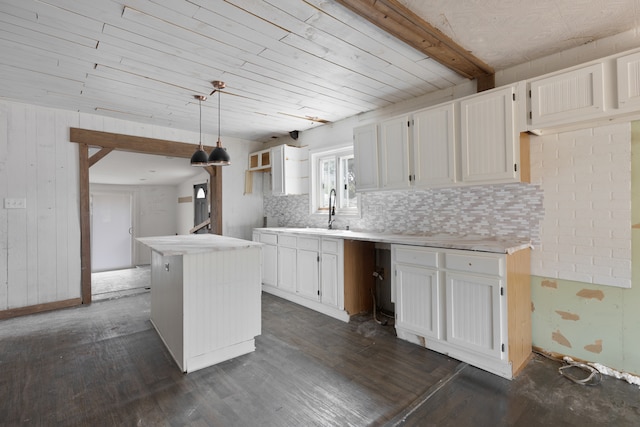 kitchen featuring a kitchen island, dark wood-type flooring, hanging light fixtures, sink, and white cabinets