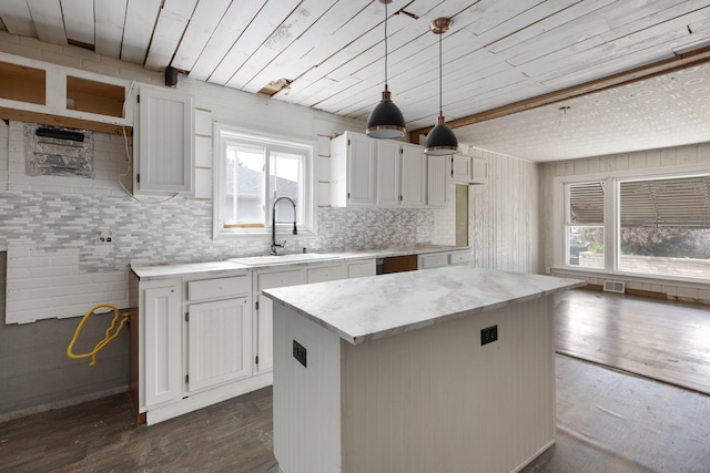 kitchen with hanging light fixtures, white cabinetry, dark wood-type flooring, sink, and a center island