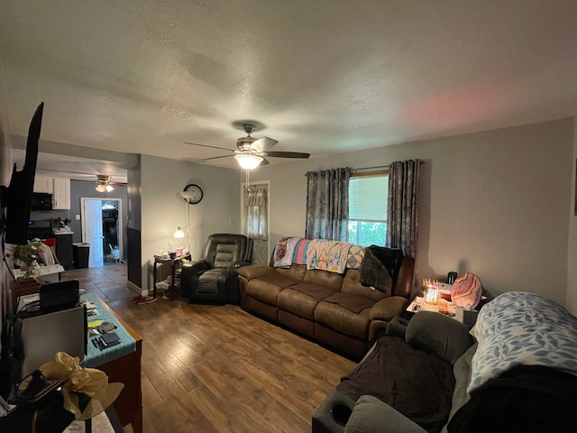 living room with a textured ceiling, hardwood / wood-style floors, and ceiling fan