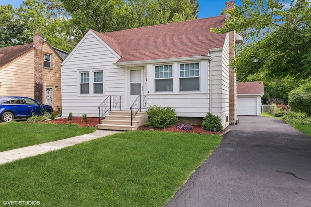 view of front facade featuring a garage, an outbuilding, and a front lawn