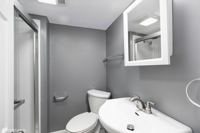 bathroom featuring walk in shower, sink, and toilet