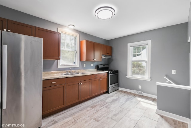 kitchen featuring light tile patterned flooring, sink, light stone countertops, and stainless steel appliances