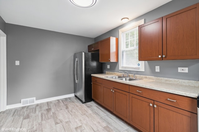 kitchen with sink, stainless steel refrigerator, and light stone countertops