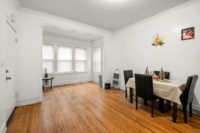 dining space with light wood-type flooring and ornamental molding