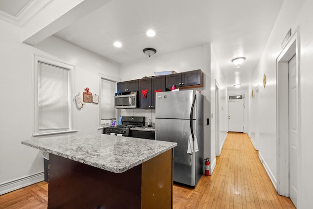 kitchen with appliances with stainless steel finishes, a kitchen breakfast bar, backsplash, light hardwood / wood-style flooring, and a center island