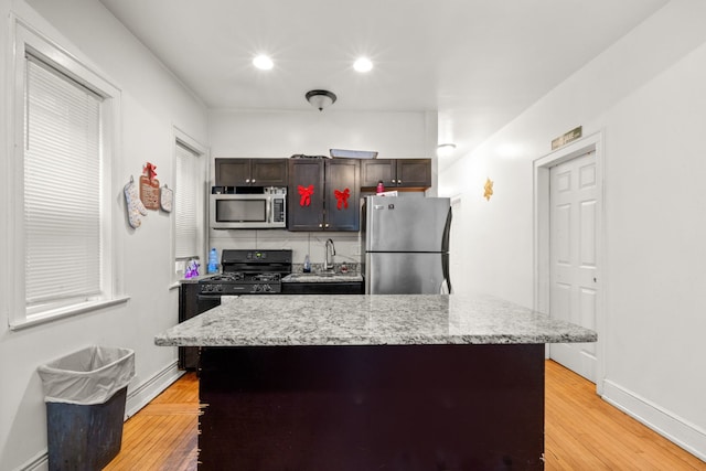 kitchen with dark brown cabinetry, a center island, light hardwood / wood-style floors, and appliances with stainless steel finishes