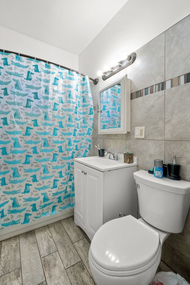 bathroom featuring vanity, toilet, tile walls, and walk in shower