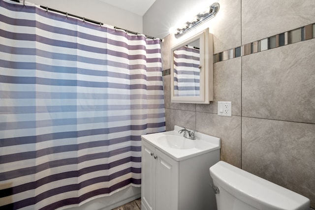 full bathroom featuring backsplash, toilet, shower / bath combo with shower curtain, vanity, and tile walls