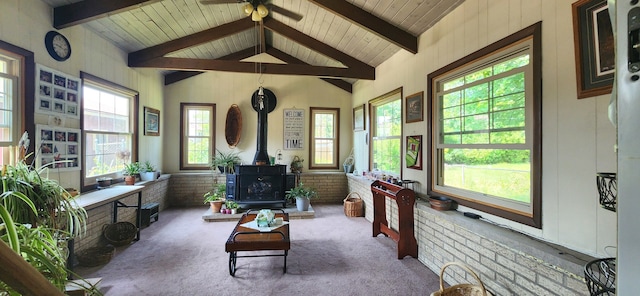 sunroom with vaulted ceiling with beams, a wood stove, ceiling fan, and wood ceiling