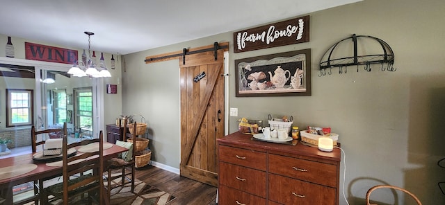 dining area with a notable chandelier, a barn door, and dark hardwood / wood-style flooring