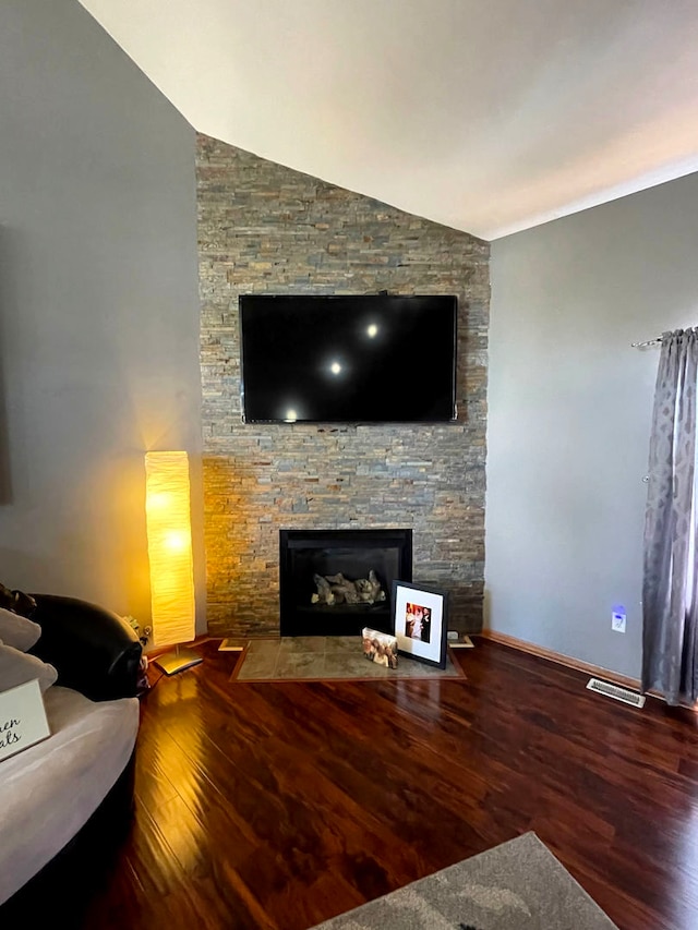 living room featuring wood-type flooring, a stone fireplace, and lofted ceiling