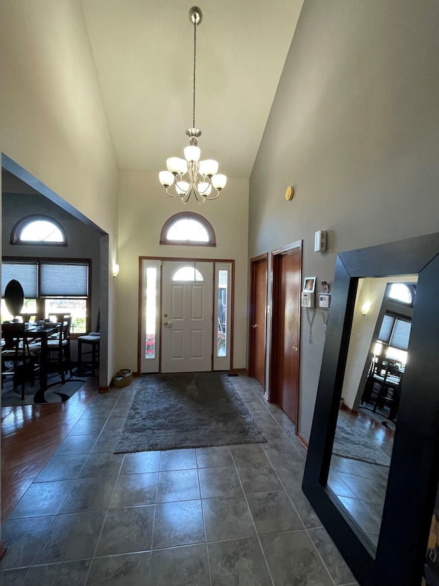 tiled entryway featuring a chandelier and high vaulted ceiling