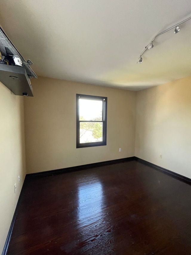 empty room featuring track lighting and hardwood / wood-style flooring