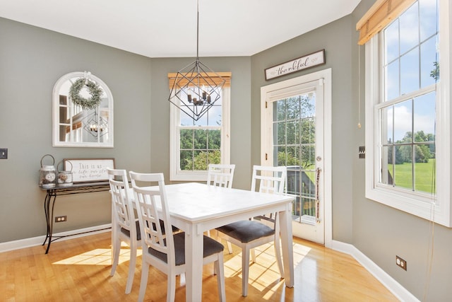 dining room with baseboards, light wood finished floors, and an inviting chandelier