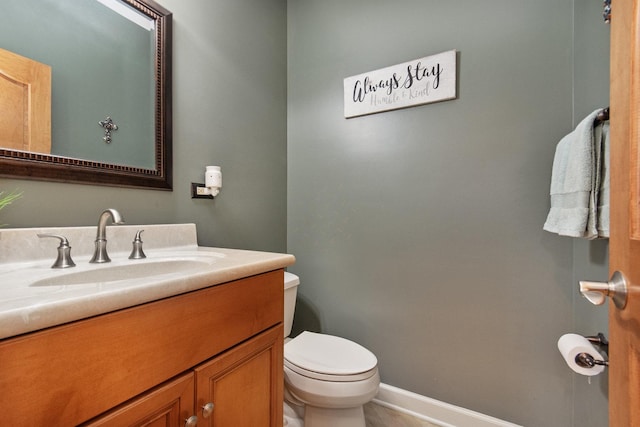 bathroom with toilet, vanity, and baseboards