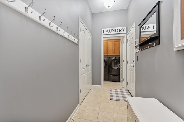 mudroom with light tile patterned floors, baseboards, and washer and dryer