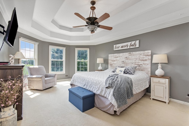 bedroom featuring light carpet, a tray ceiling, ornamental molding, and baseboards