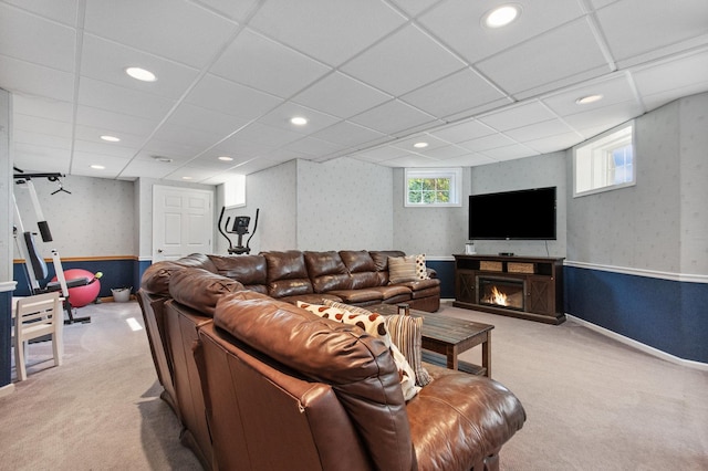 living area featuring light carpet, a warm lit fireplace, wallpapered walls, a paneled ceiling, and recessed lighting