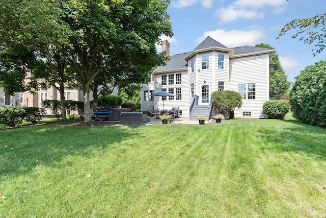 rear view of property with a patio, a yard, and a chimney