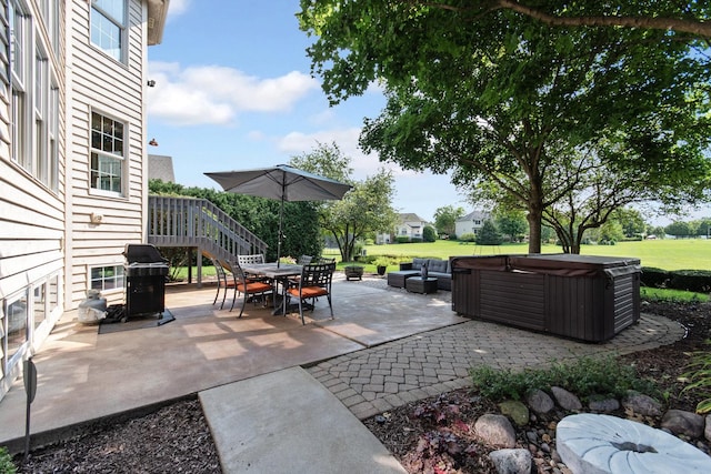 view of patio / terrace featuring stairs, outdoor dining space, and a hot tub